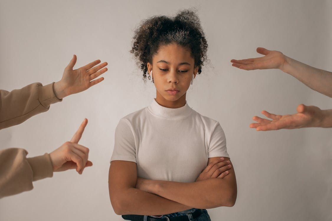 A person looking down while people scold her