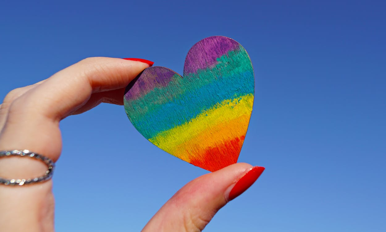 A person holding a heart in Pride colors